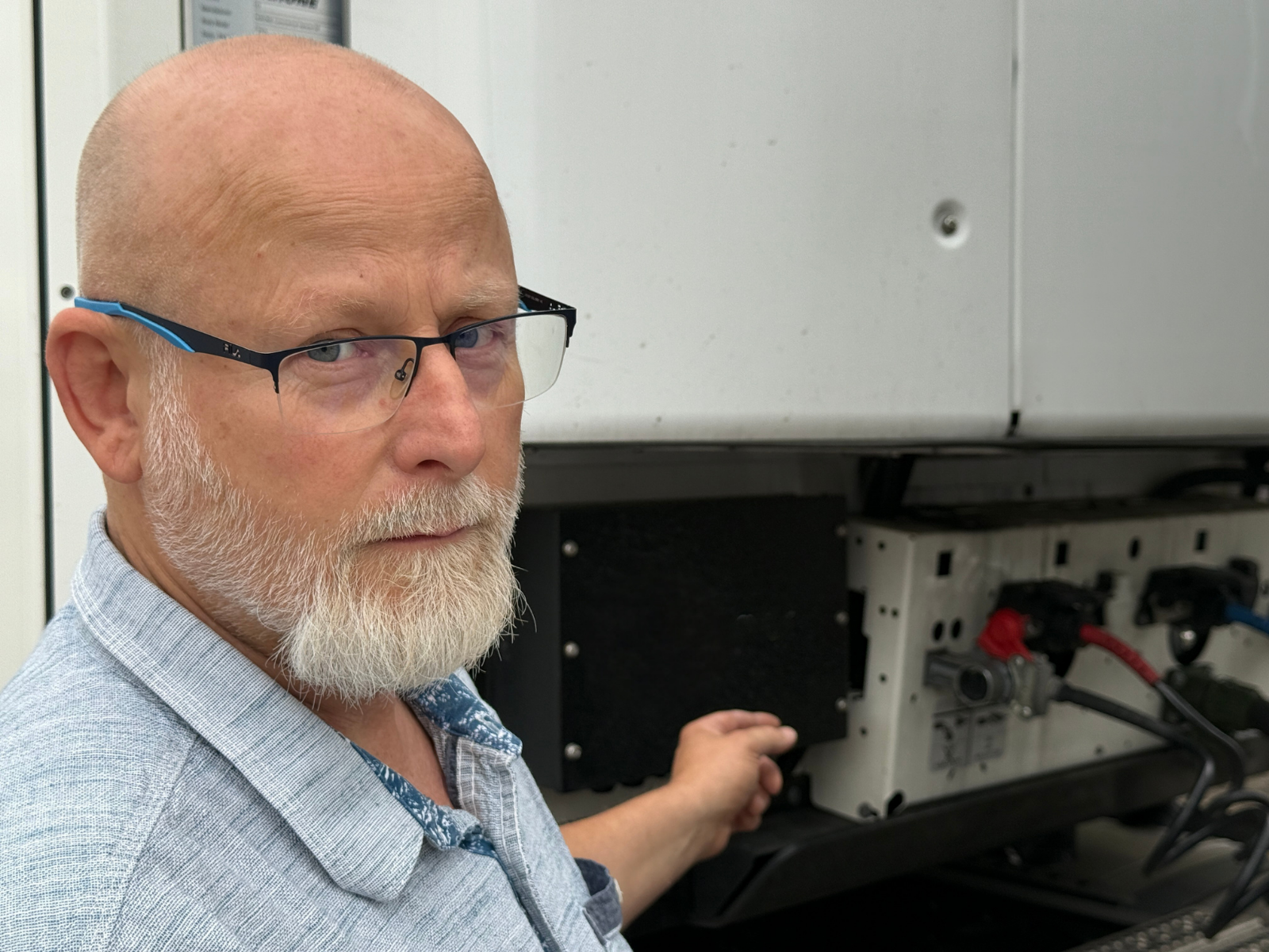 Älterer Mann mit Brille und Bart arbeitet an technischem Gerät.